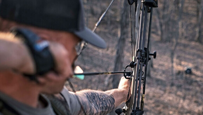Practice Essentials To Elevate Your Bowhunting Game Article Over the shoulder view of bow hunter aiming bow from an elevated position