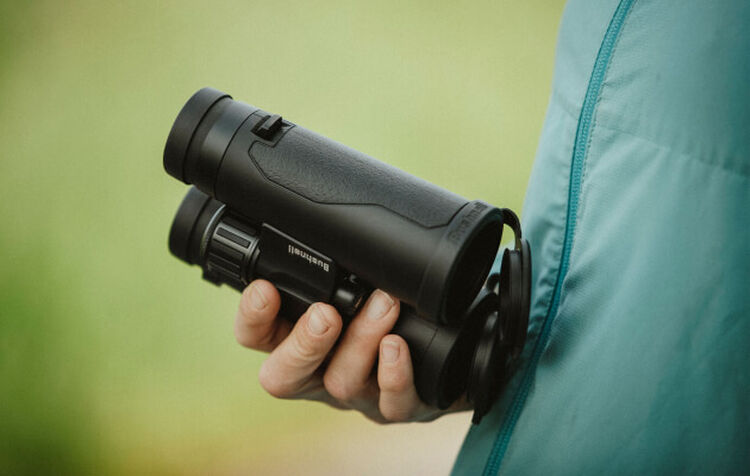 Built To Stand Up To The Elements Hand holding a pair of Bushnell Binoculars